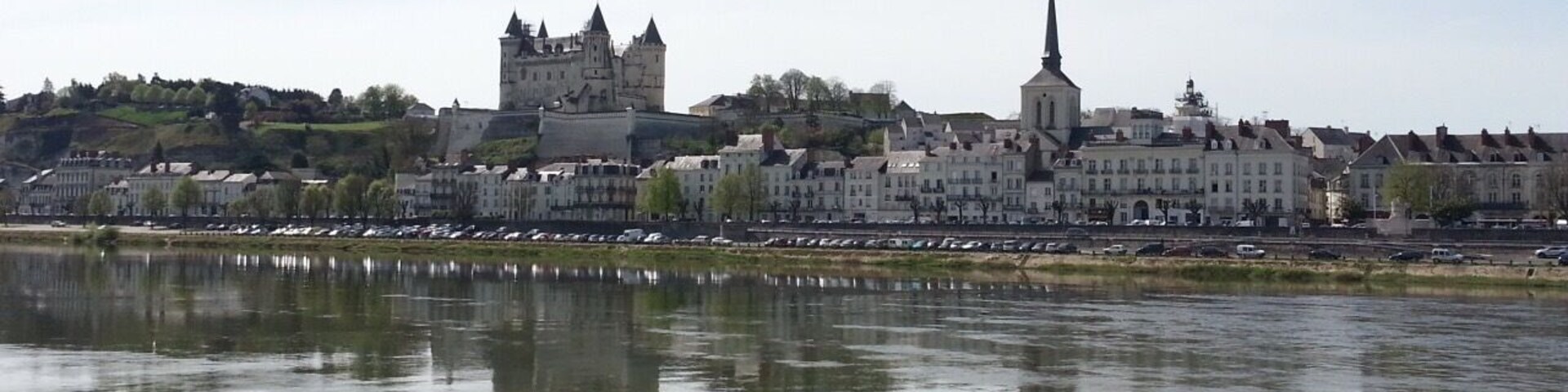 A river with a castle and a church on the opposite bank.