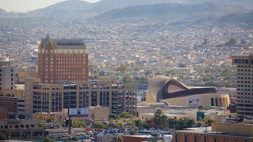 A cityscape with a prominent hotel, a distinctive building with a curved roof, and a densely populated urban area with mountains in the background.