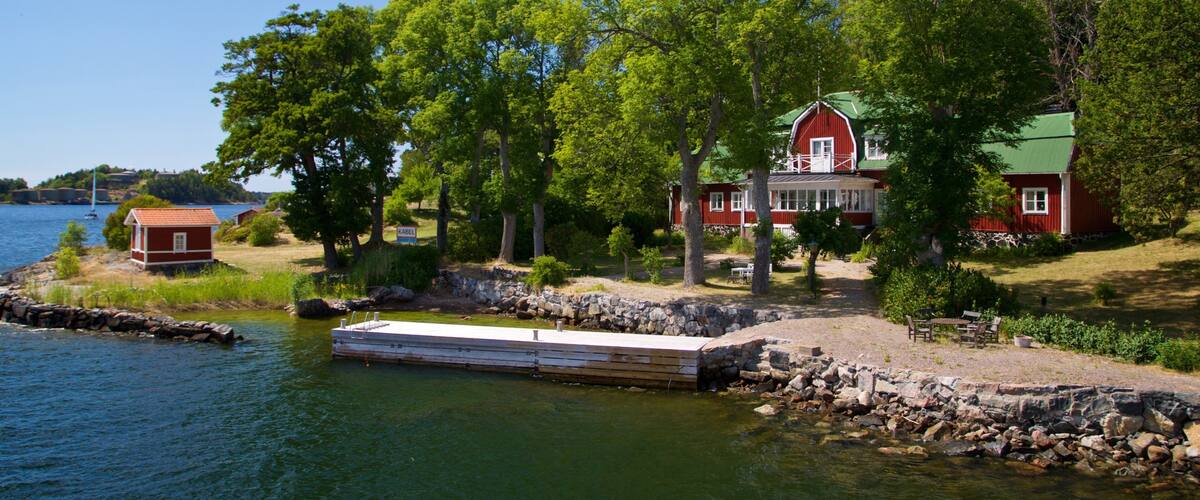 Una propiedad junto al lago con una casa roja, muelle y vegetación circundante.