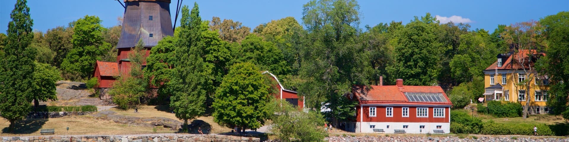 A water tower, a red barn, and a yellow house by a lake.