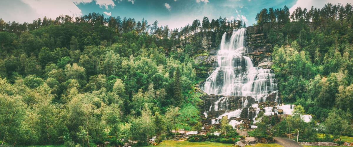 A waterfall cascading down a rocky cliff surrounded by dense forest.