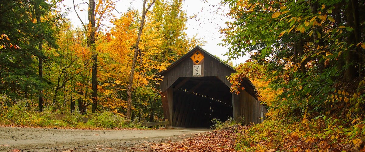 A covered bridge surrounded by autumn foliage.