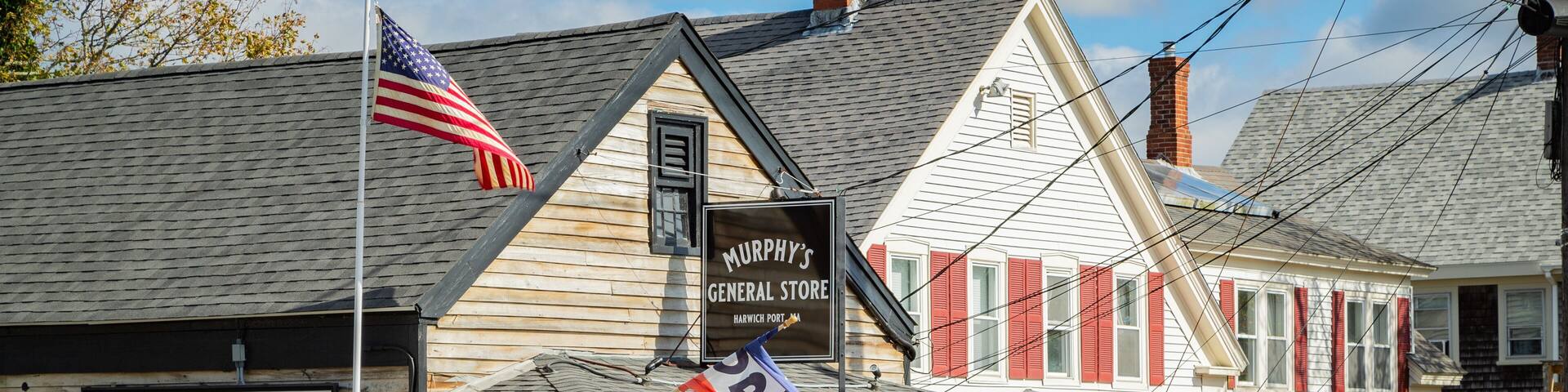 A storefront with a sign for Murphy's General Store, an American flag, and a Halloween decoration.