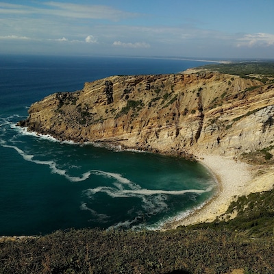Un acantilado costero con una playa y olas del océano.