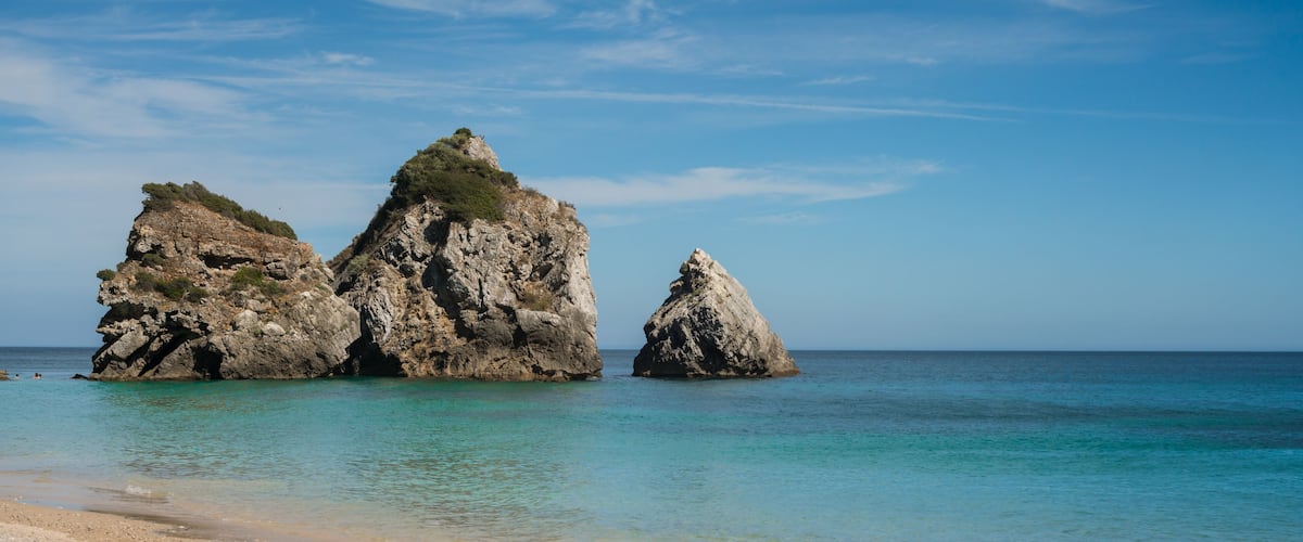 Una playa con formaciones rocosas y agua turquesa cristalina.