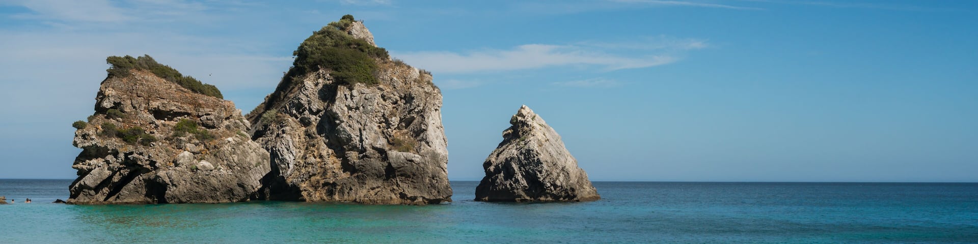A beach with rocky formations and clear turquoise water.