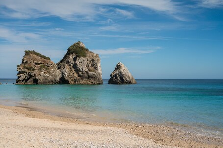 A beach with rocky formations and clear turquoise water.