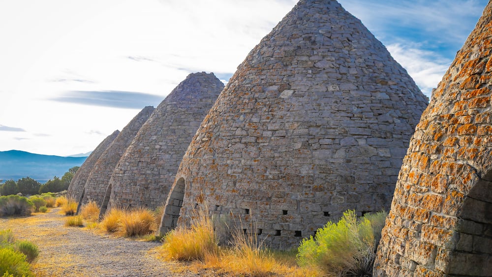 A series of stone structures with a clear sky and distant mountains.