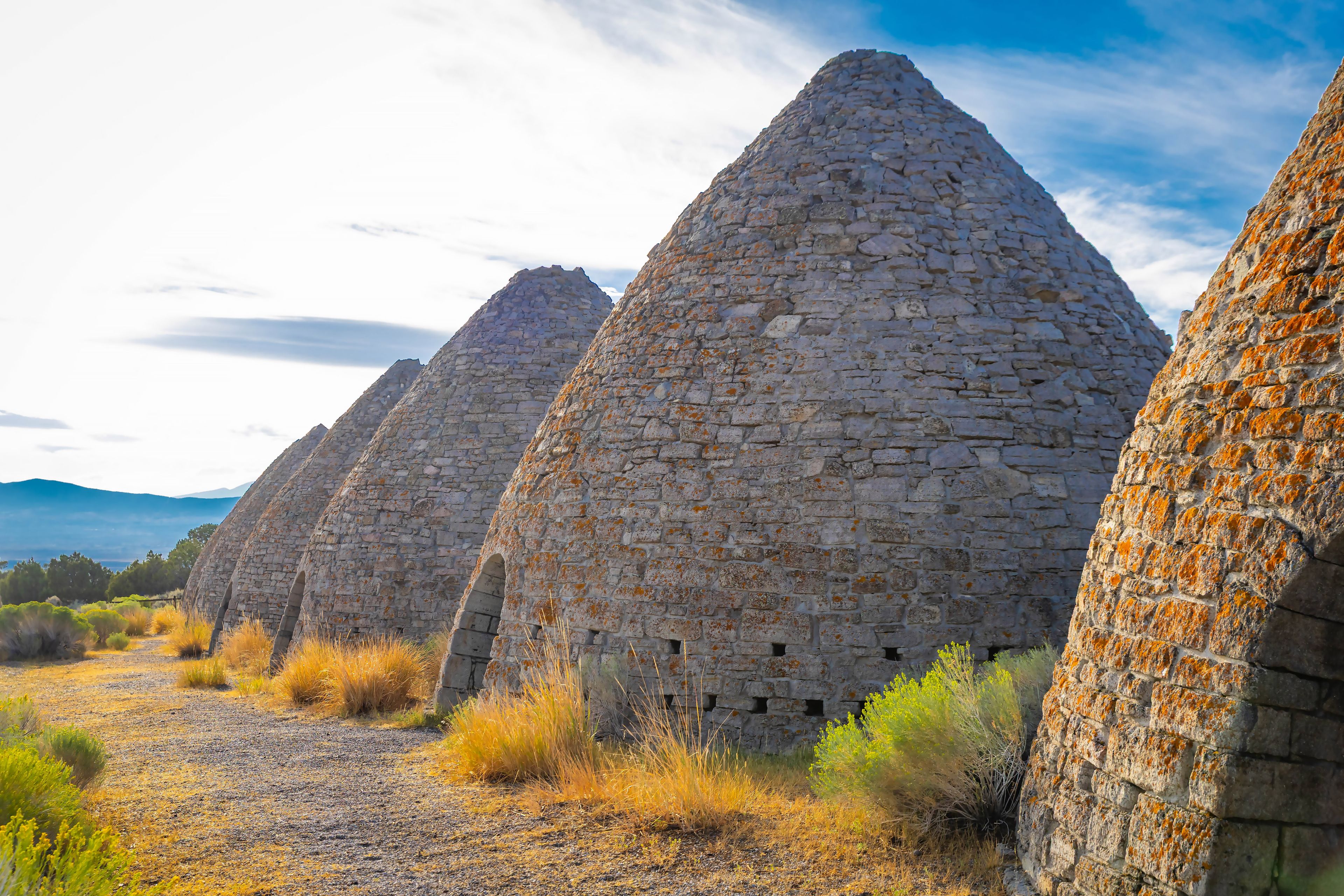 A series of stone structures with a clear sky and distant mountains.