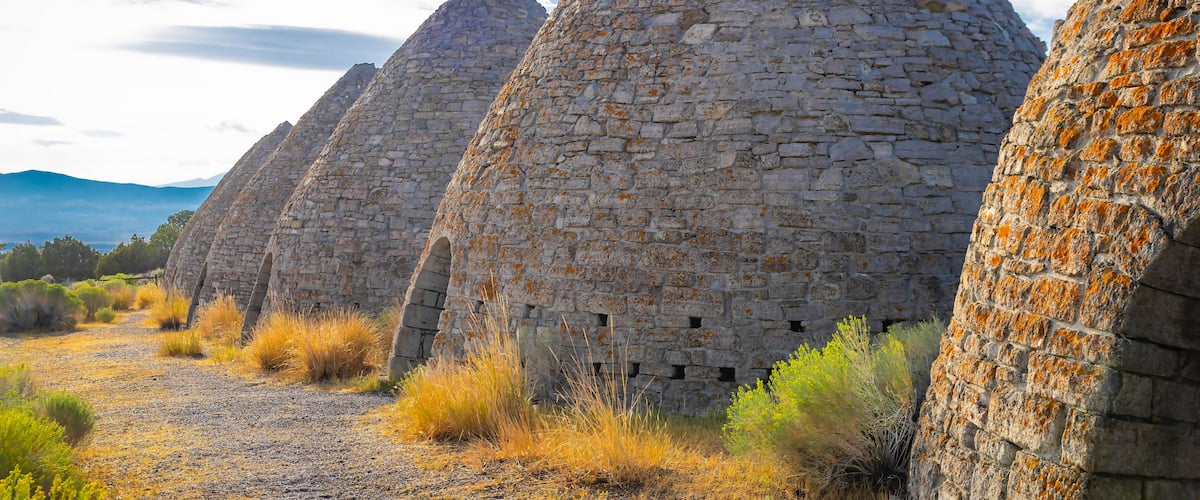 A series of stone structures with a clear sky and distant mountains.