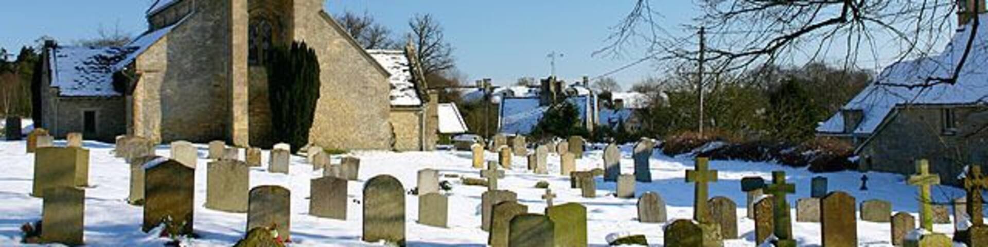 St Mary's parish church, Swinbrook, Oxfordshire, seen from the west in sun and snow