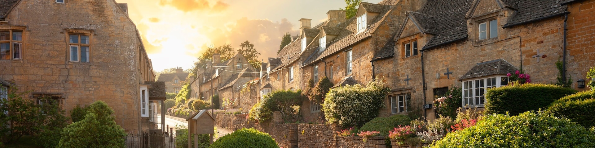 A quaint village with stone buildings, a cobblestone street, and lush greenery.