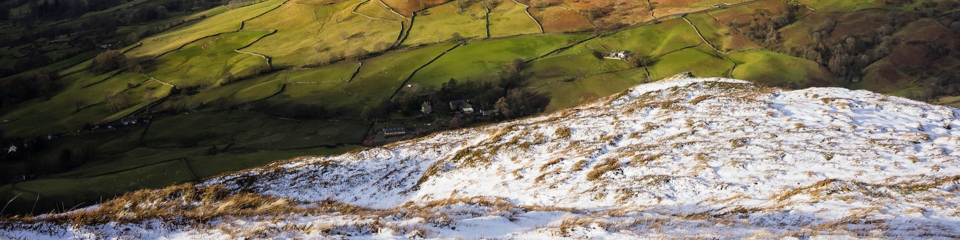 A snow-covered mountain range with green valleys and a small village.