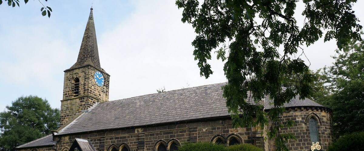 A historic church with a tall steeple and a clock, surrounded by well-maintained greenery.