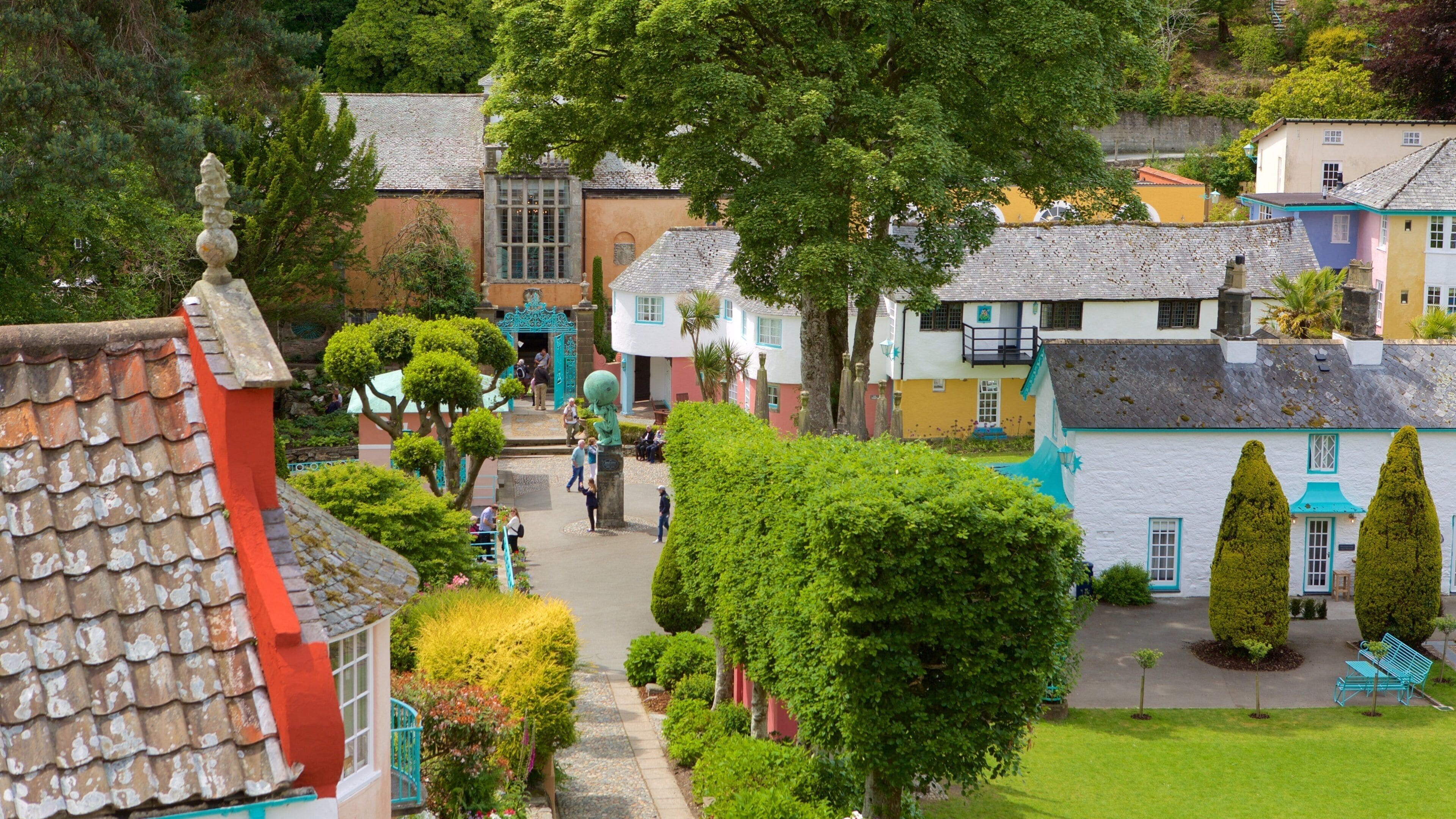 A quaint village with colorful buildings, a central pathway, and neatly trimmed trees.