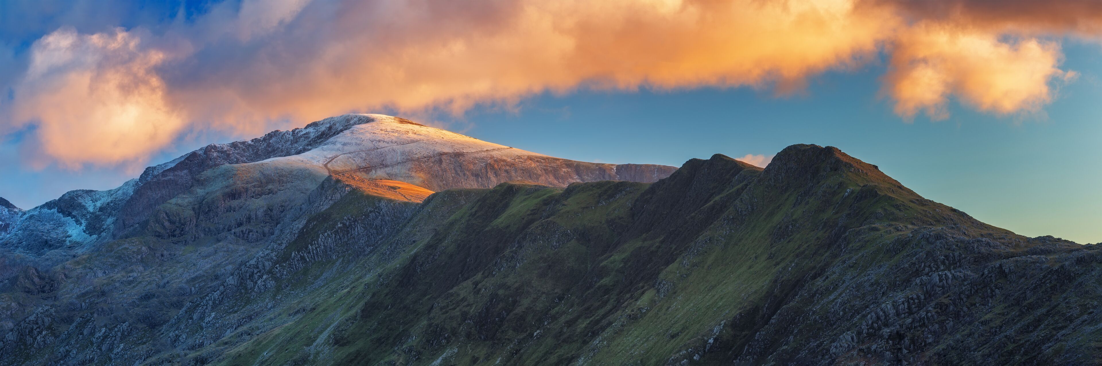A mountain range with snow-capped peaks and a clear sky.