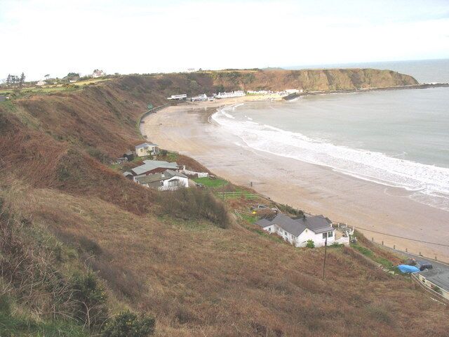 A coastal landscape with a beach, houses, and cliffs.