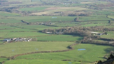 De vastes prairies verdoyantes, un petit village et des collines lointaines.