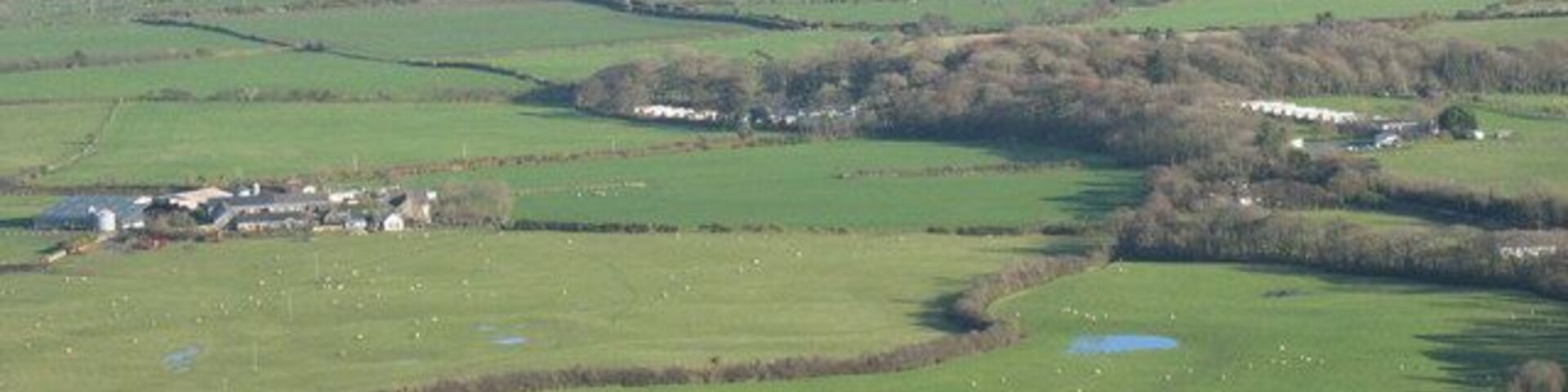 Faerdre Farm and Plas Gelliwig from Rhiw Mountain Faerdre Farm is on the left of the photo. The Caravan parks at Gelliwig form a prominent feature of the landscape as do the kettle lakes.