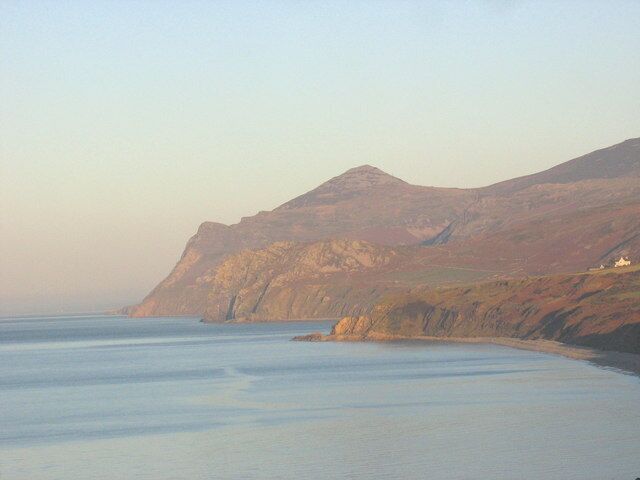 A coastal landscape with a mountain range and a calm sea.