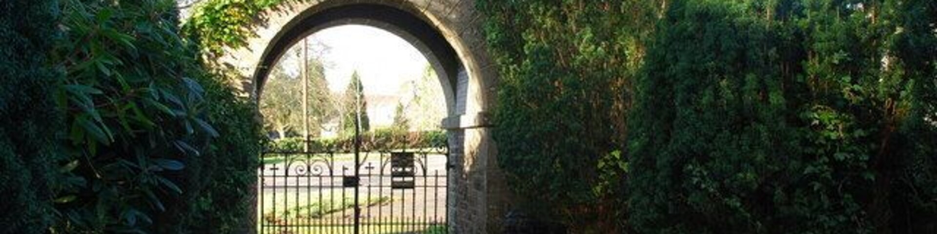A stone archway leading to a gated area surrounded by greenery.