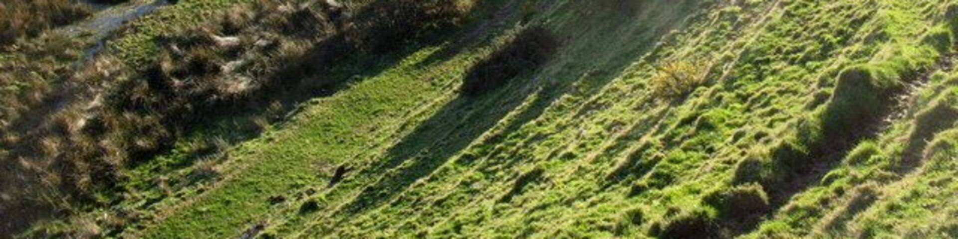 Near to Llwyndyrys, Gwynedd, Wales, Great Britain. A meandering reach of Afon Erch upstream of the elbow of capture. The 90 degree bend in the course of the river marks the point of river capture. The wind gap through which the river formerly flowed can be seen on the right. Soil creep terracetes are a prominent feature of the slope in the foreground.