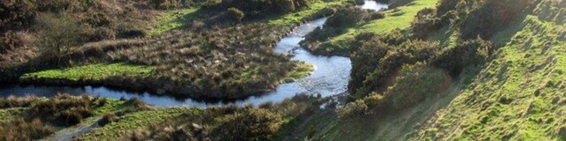Near to Llwyndyrys, Gwynedd, Wales, Great Britain. A meandering reach of Afon Erch upstream of the elbow of capture. The 90 degree bend in the course of the river marks the point of river capture. The wind gap through which the river formerly flowed can be seen on the right. Soil creep terracetes are a prominent feature of the slope in the foreground.