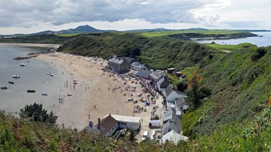 A coastal town with a sandy beach, boats in the water, and green hills in the background.