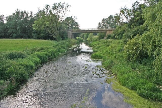 The River Welland at Duddington. Standing on the old stone bridge on Mill Street with one foot in Rutland and the other in Northamptonshire. The county boundary follows the river for several miles. The new bridge in the photograph carries the A47 over the river right on the boundary with SK9801. See TF2524 and other squares near Spalding for more pictures of the River Welland as it nears The Wash.