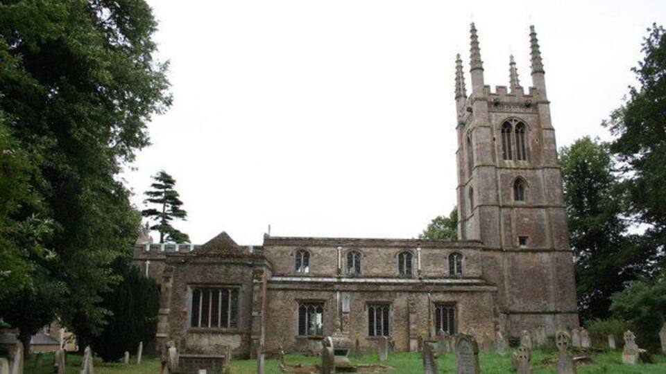 A historic church with a tall tower and a cemetery in front.