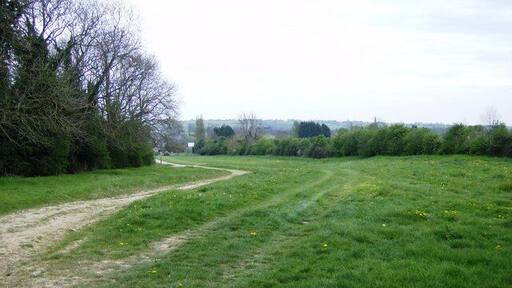 Beyond Home Farm A footpath runs down this obvious farm track towards Home Farm, but another runs off to the right; the stile is just visible as a white blob in the hedgerow near the right hand edge of the picture.