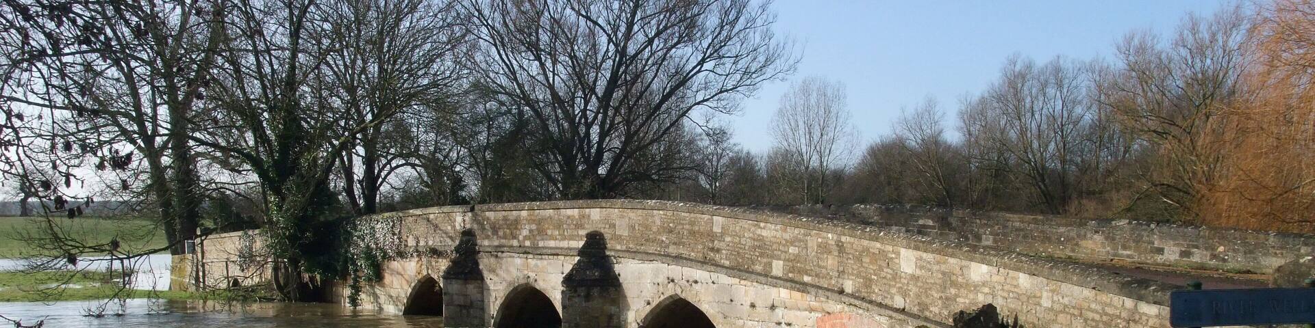 A swollen River Welland passing beneath the old bridge in Duddington