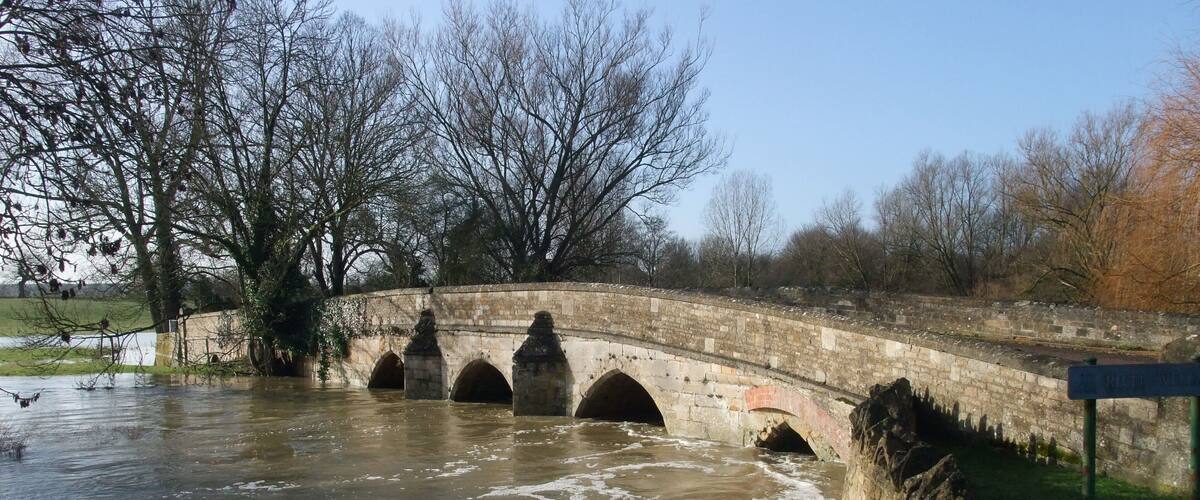 A stone bridge over a river with a sign reading "River Walk."