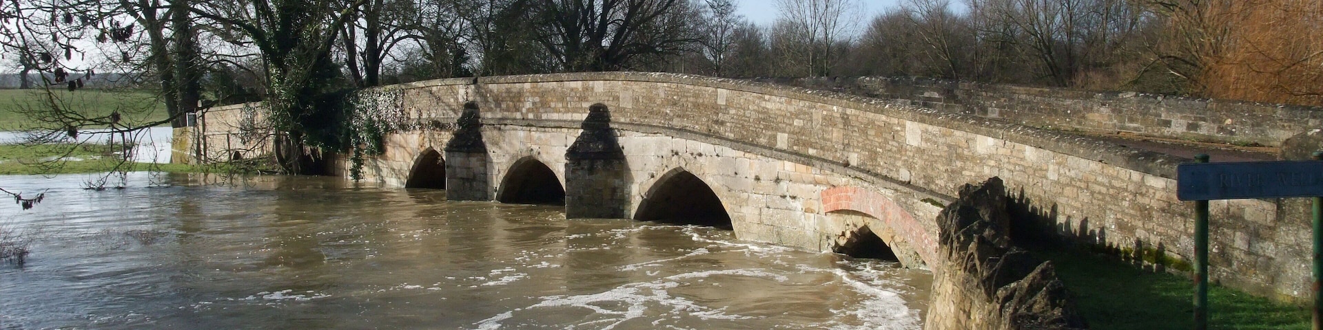 A stone bridge over a river with a sign reading "River Walk."