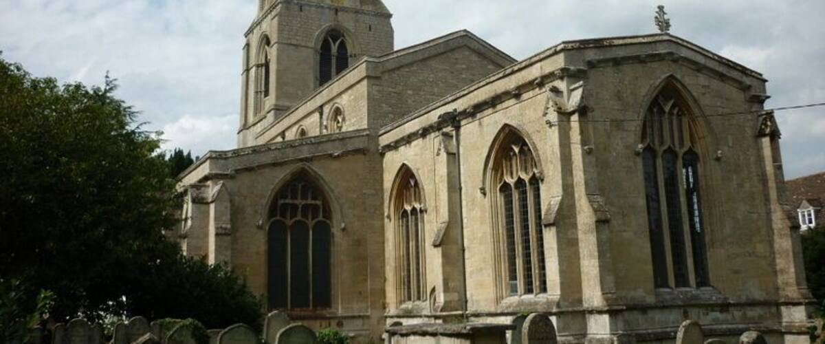 A church with a tall spire and arched windows, surrounded by gravestones.