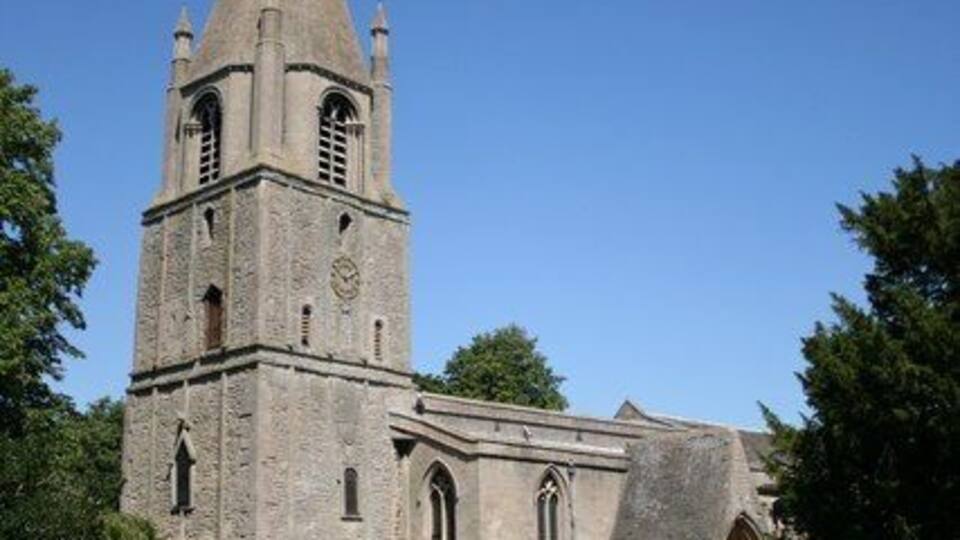 A historic church with a tall bell tower and a graveyard in front.