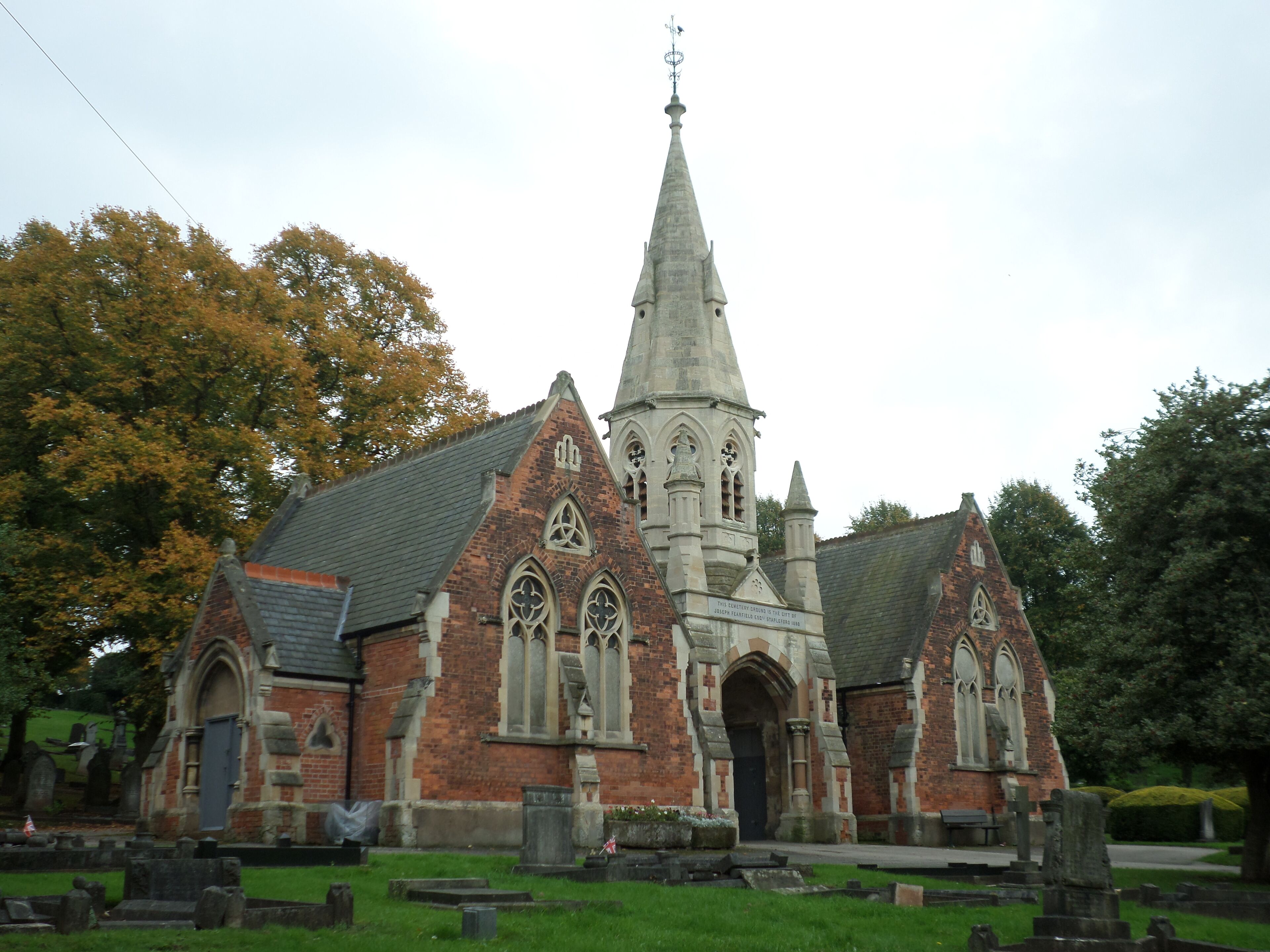 A historic church with a tall spire, brick walls, and pointed arches.
