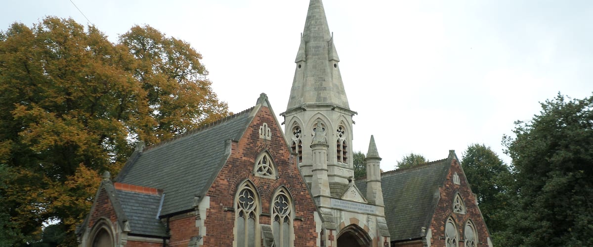 A historic church with a tall spire, brick walls, and pointed arches.