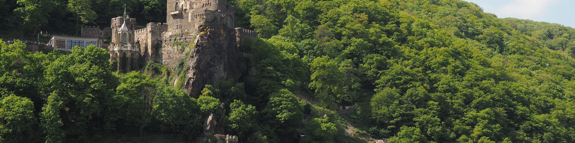 Um castelo numa colina, um rio e um barco.
