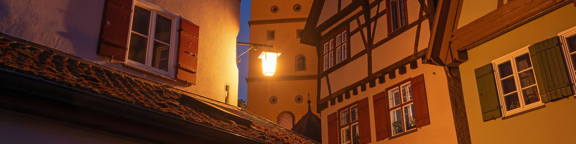 Traditional timber framed houses with illuminated Segringer Tor gate tower at night. Dinkelsbuehl, Bavaria, Germany.