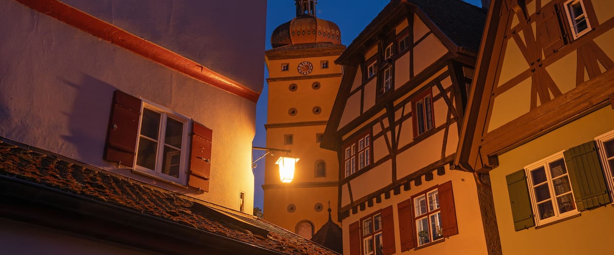 A traditional European town with half-timbered houses and a prominent tower with a clock.