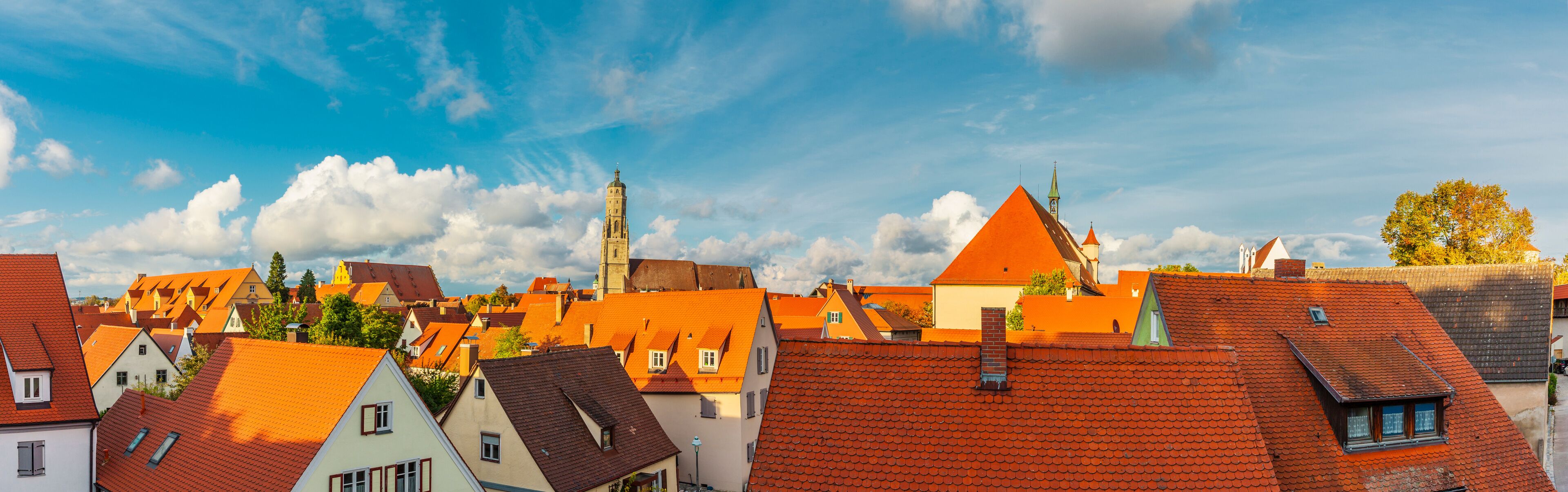 A town with red-roofed buildings, a prominent church tower, and a clear blue sky.