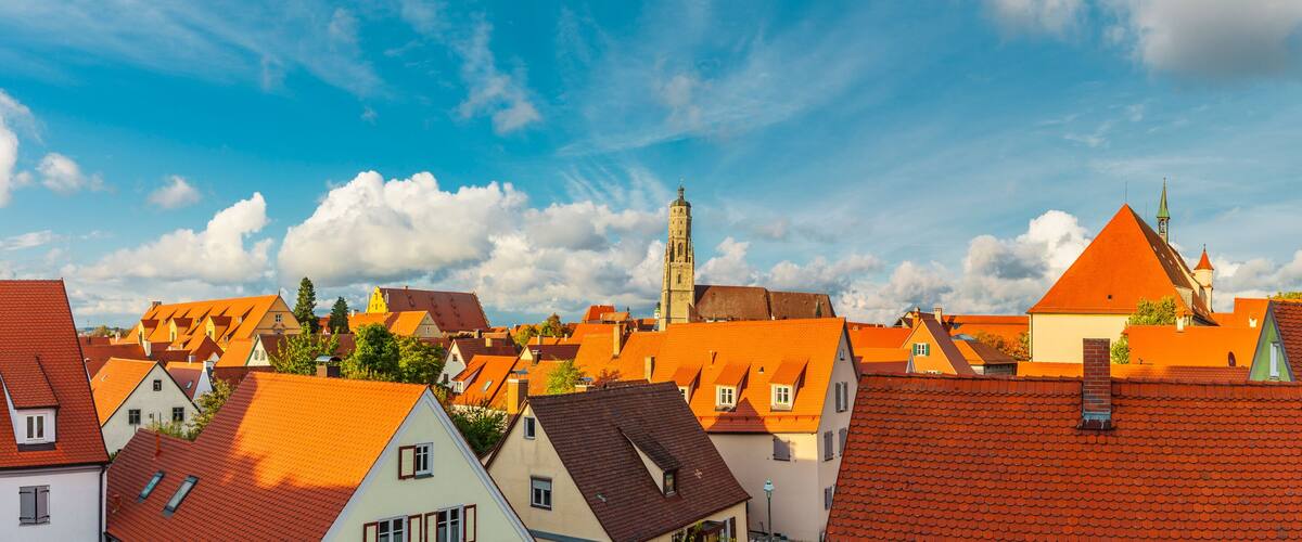 A town with red-roofed buildings, a prominent church tower, and a clear blue sky.