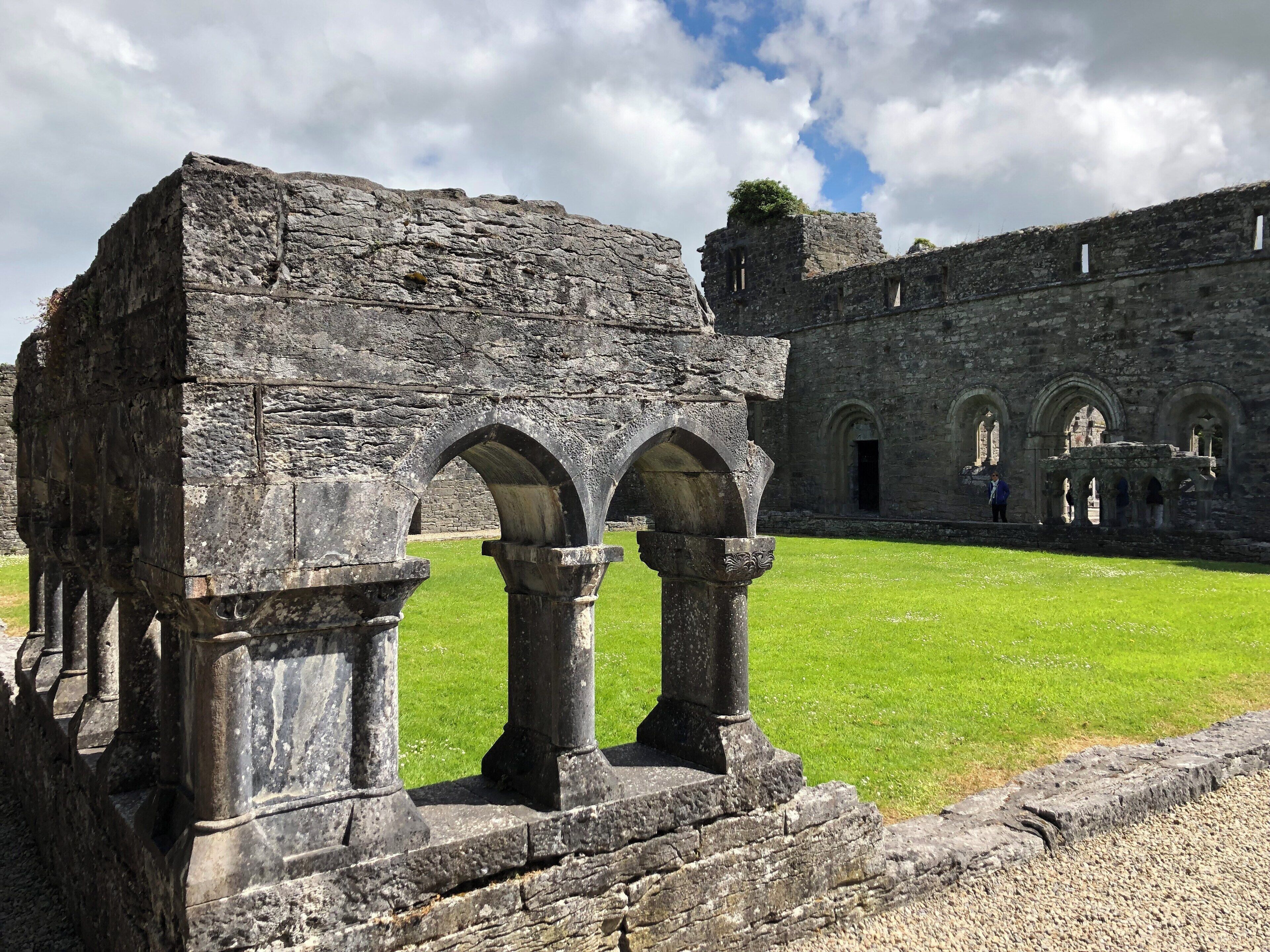 Ancient stone ruins with arches and a grassy courtyard.
