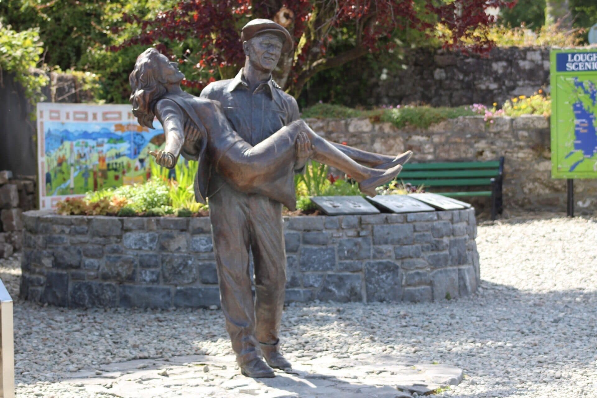 Estatua de um homem carregando uma criança em um parque.