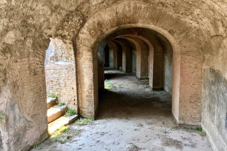 An arched corridor with brick walls and a concrete floor.