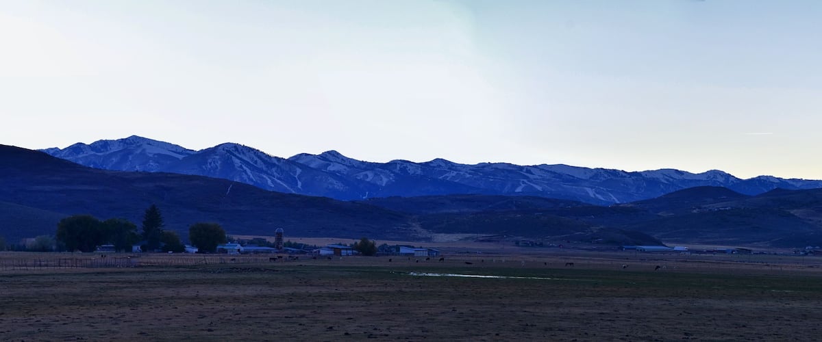 A mountainous landscape with a small village and grazing animals.