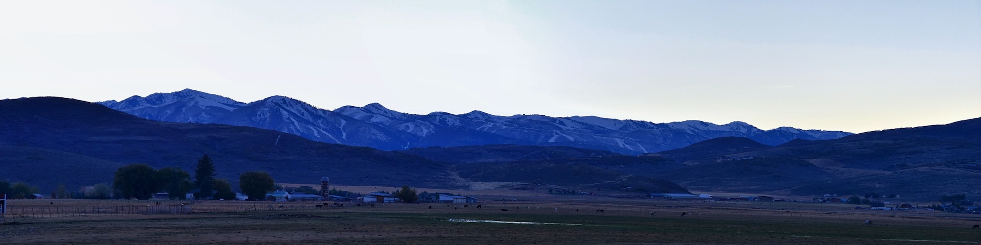 A mountainous landscape with a small village and grazing animals.