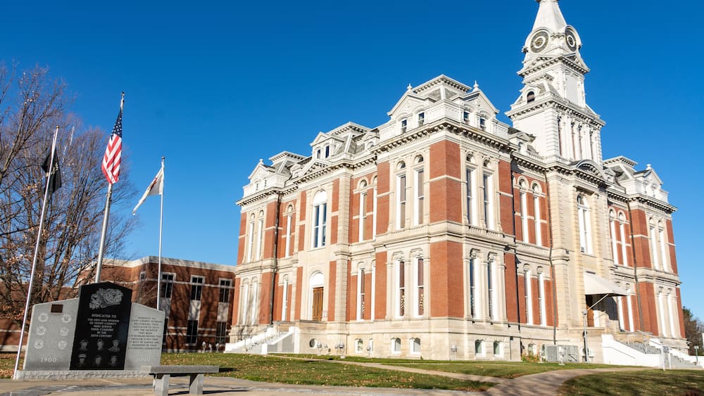 A large, historic building with a prominent clock tower and a flagpole with the American flag.