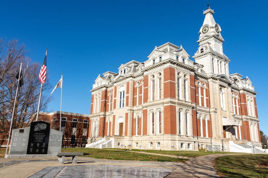 A large, historic building with a prominent clock tower and a flagpole with the American flag.
